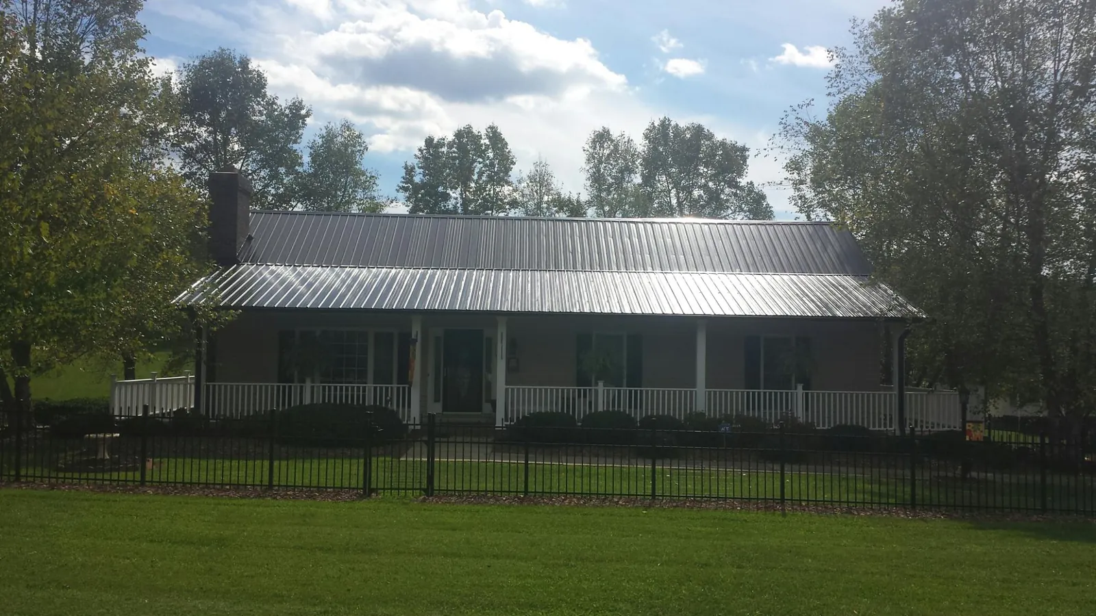 Gray metal roof on a brick ranch with a full width front porch in Morton